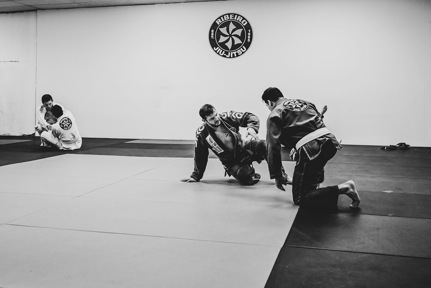Štyria muži cvičia brazílske jiu-jitsu v telocvični.